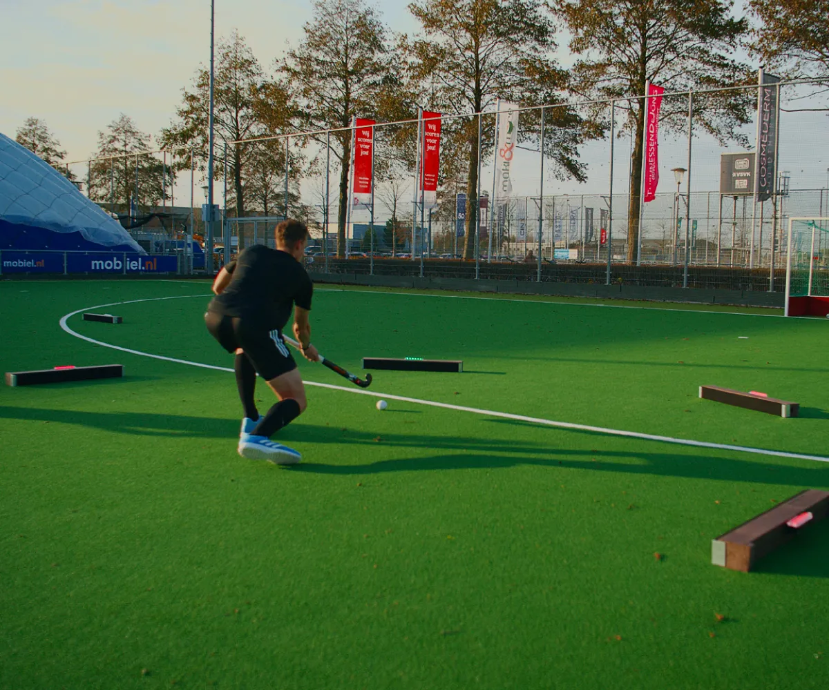 Hockeyer rent met de bal tussen de Beams door