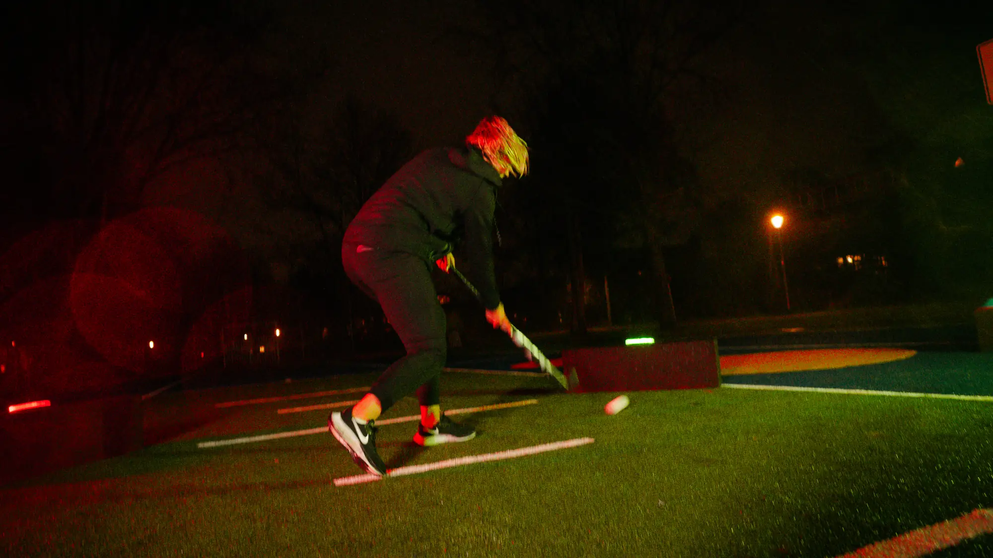 Hockey player striking at a lit Beam in the evening