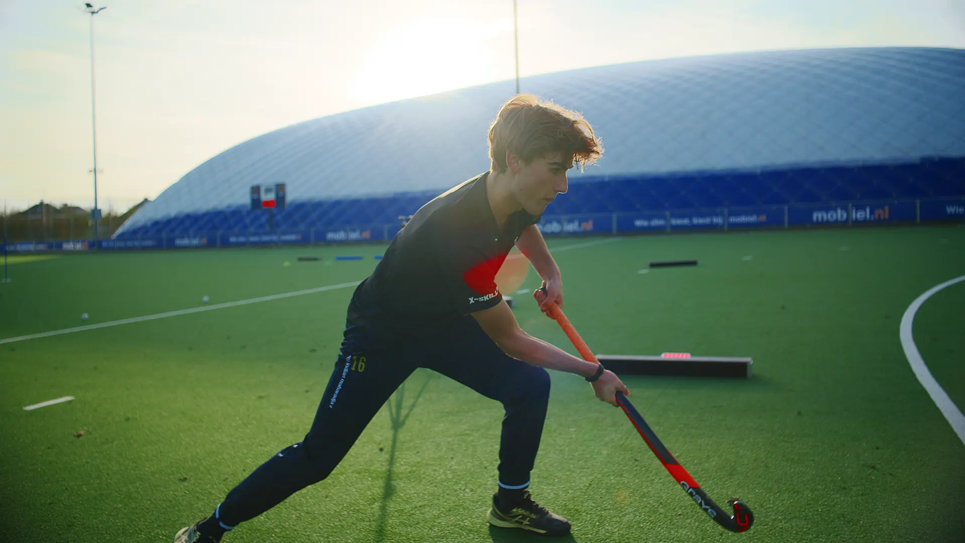 Hockeyer duwt de bal langs een Beam in het avondlicht