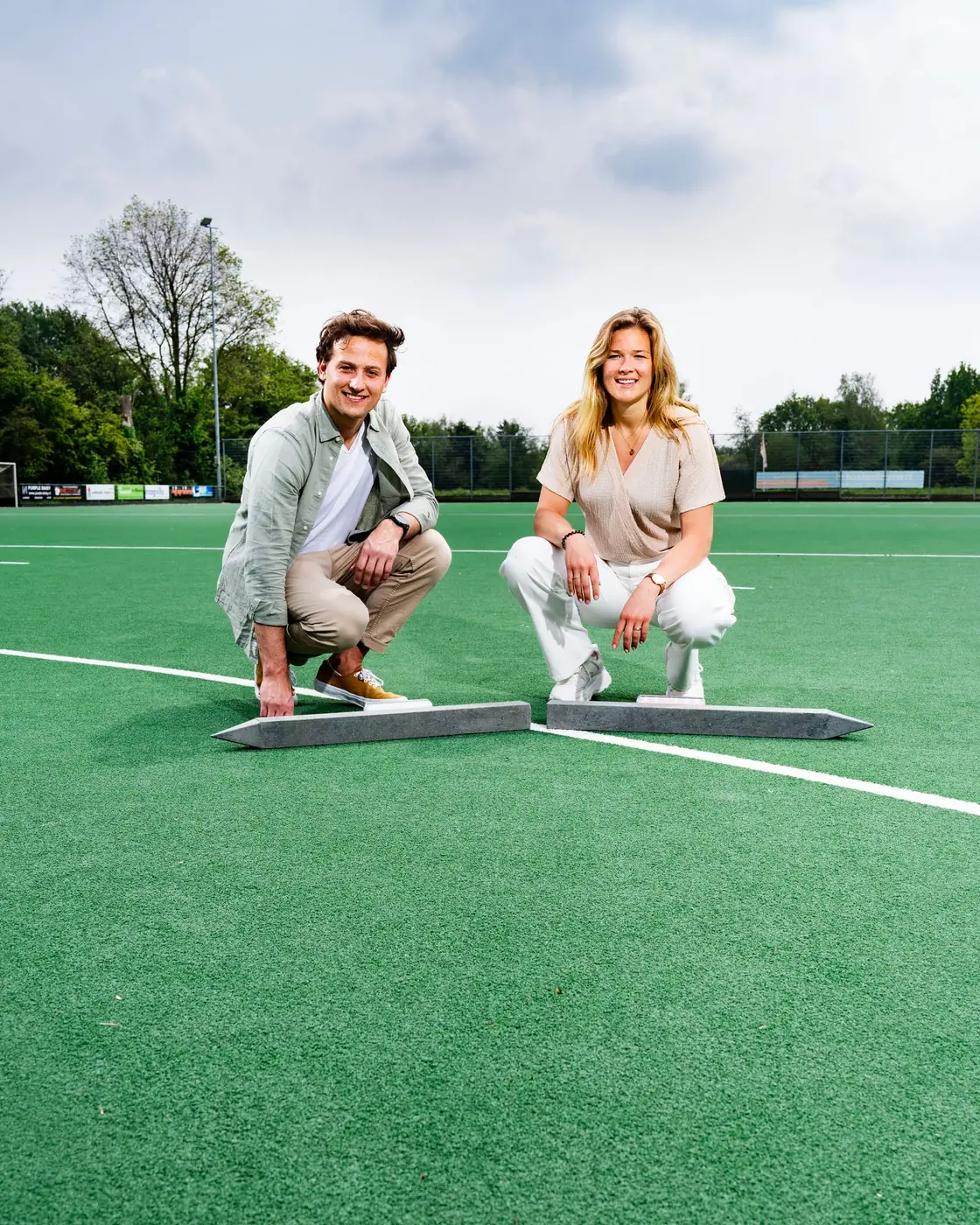 Bo-Jane and Michael crouching on the turf, two Beams forming an X between them