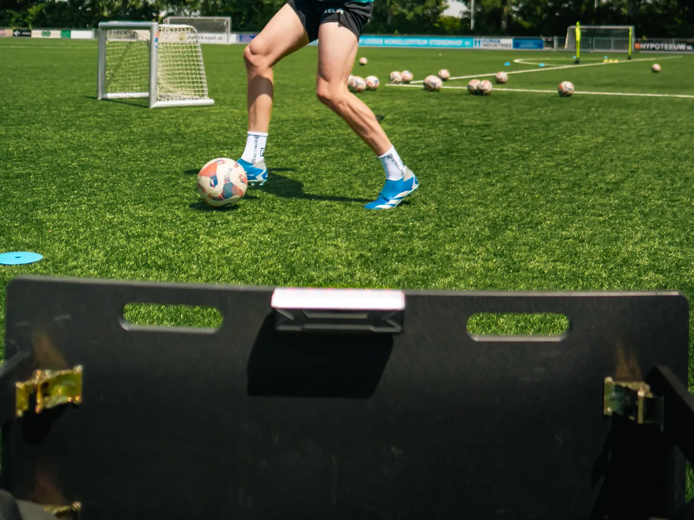Speler met bal voor de rebounder met Beam, thuis op het gras
