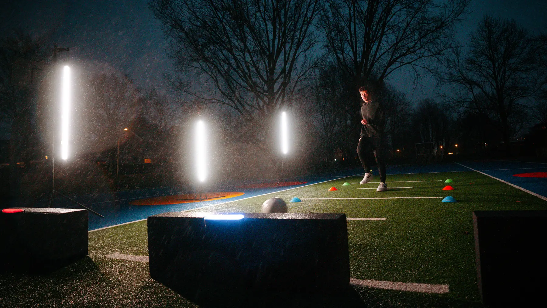 Three Beams glowing on a football pitch after dark